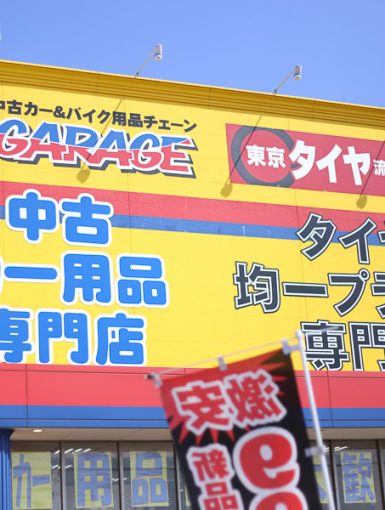 Yellow building with signs for Up Garage and Japanese text advertising a used car parts specialty store and a tire store.