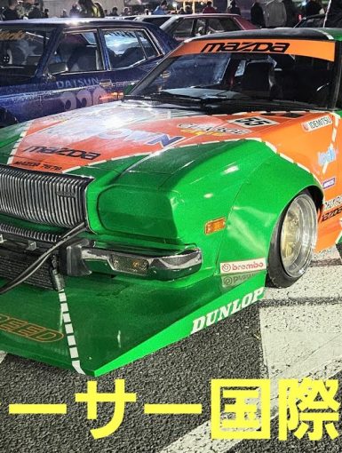 Colorful modified racing cars at a Street Racer International Exchange event in Japan, featuring a green Mazda.