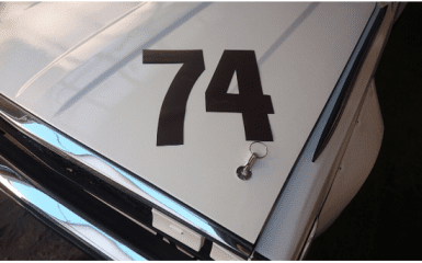 Alt text: Close-up of a car hood with the number 74 and a keychain lying on it