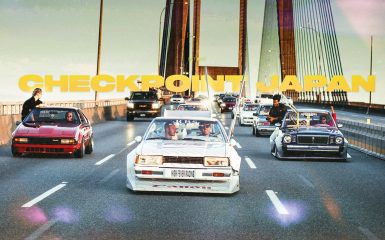 Group of modified cars driving on a Japanese bridge under the text Checkpoint Japan, setting sun in the distance.