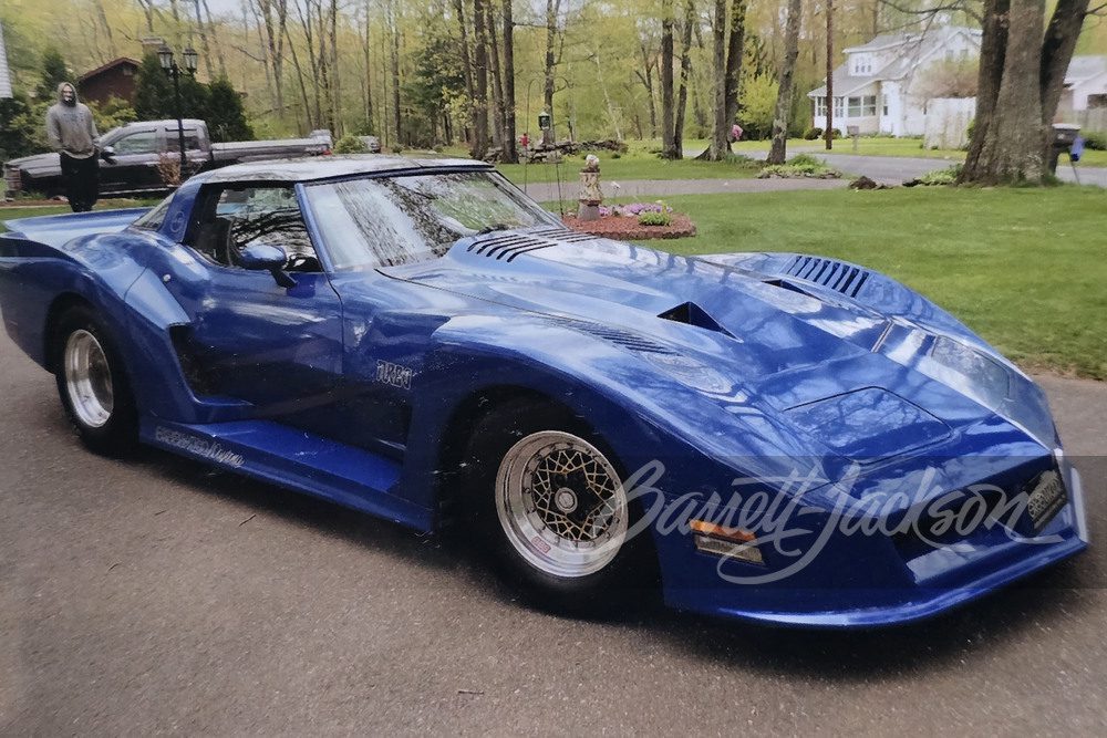 Custom blue sports car parked on a driveway, showcasing sleek design and Barrett-Jackson branding.