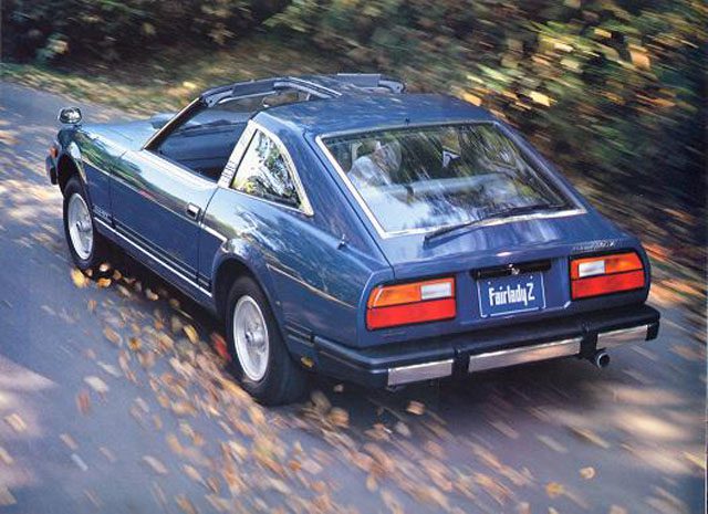 Vintage blue Fairlady Z sports car driving on a leafy road in autumn.