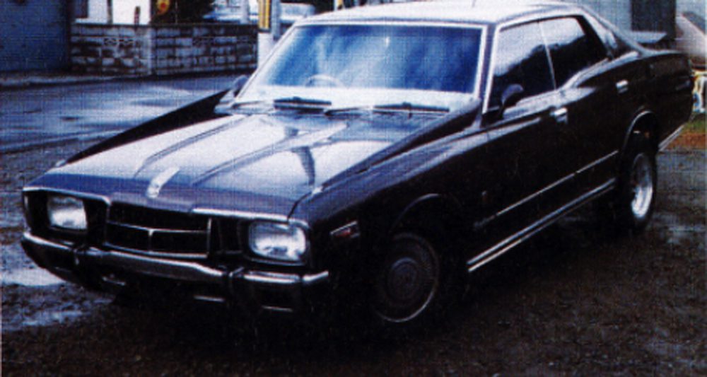 Classic black vintage car parked on a wet street, showcasing a retro design with shiny chrome accents.