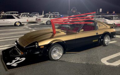 Custom vintage Nissan sports car at night car meet, featuring distinctive body modifications and bold styling.