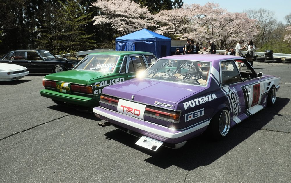 Modified Toyota GX61 and GX71  cars at a nonsuri event with cherry blossoms in the background.