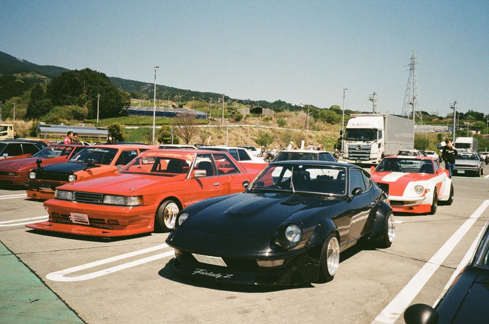 Vintage sports cars parked at an outdoor car meet on a sunny day.