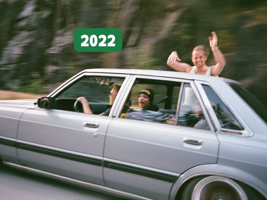 People enjoying a ride in a vintage car with a 2022 sticker on the window, capturing joyful moments.