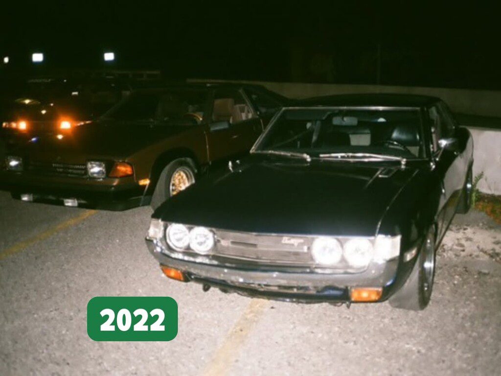 Vintage cars parked at night, featuring a black model in the foreground, with a 2022 label in the corner.
