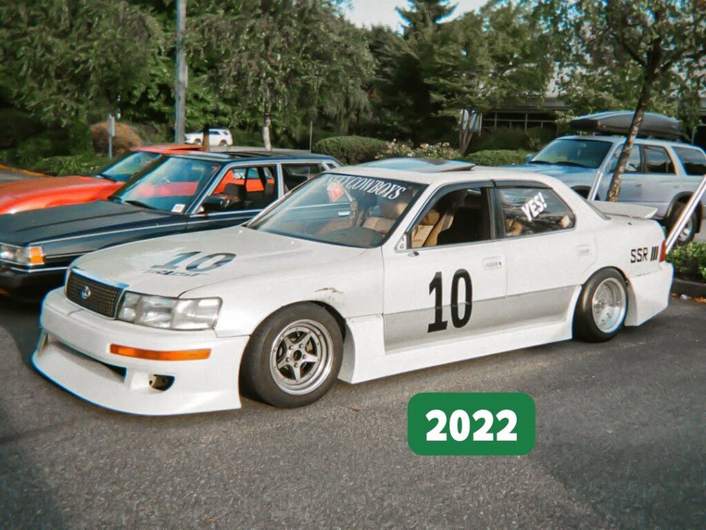 Modified white race car with number 10 parked at a car meet in 2022, SSR wheels, and distinctive decals.