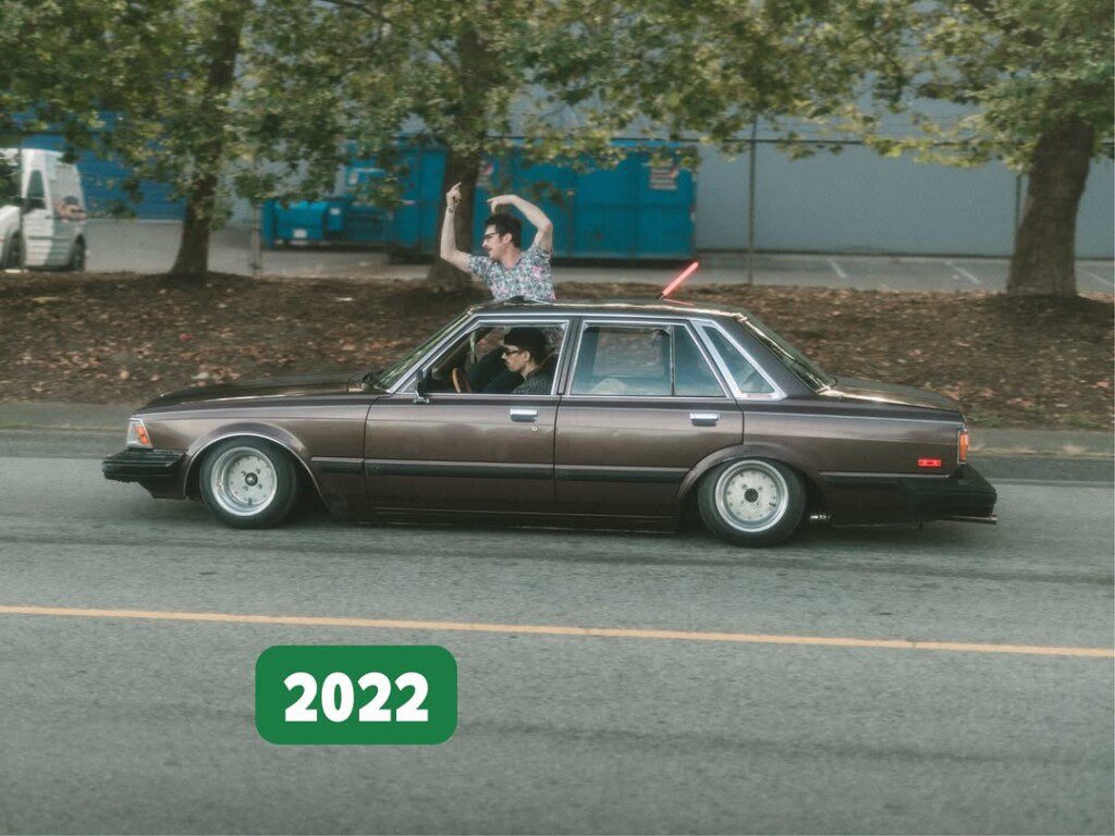 Vintage car cruising with enthusiastic passenger in 2022, capturing retro vibes and outdoor adventure.