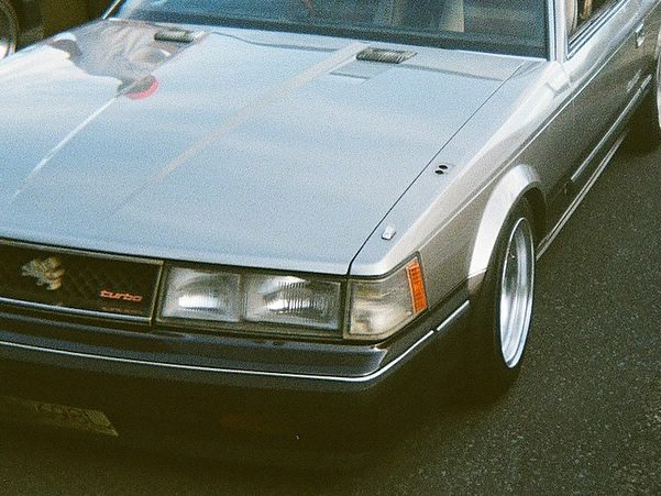 Vintage silver turbo car on asphalt, showcasing classic design with sleek lines and distinctive headlights.