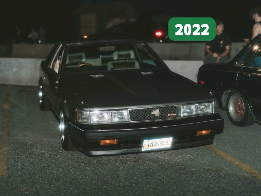 Vintage black car parked at night with 2022 overlay, showcasing classic design features.