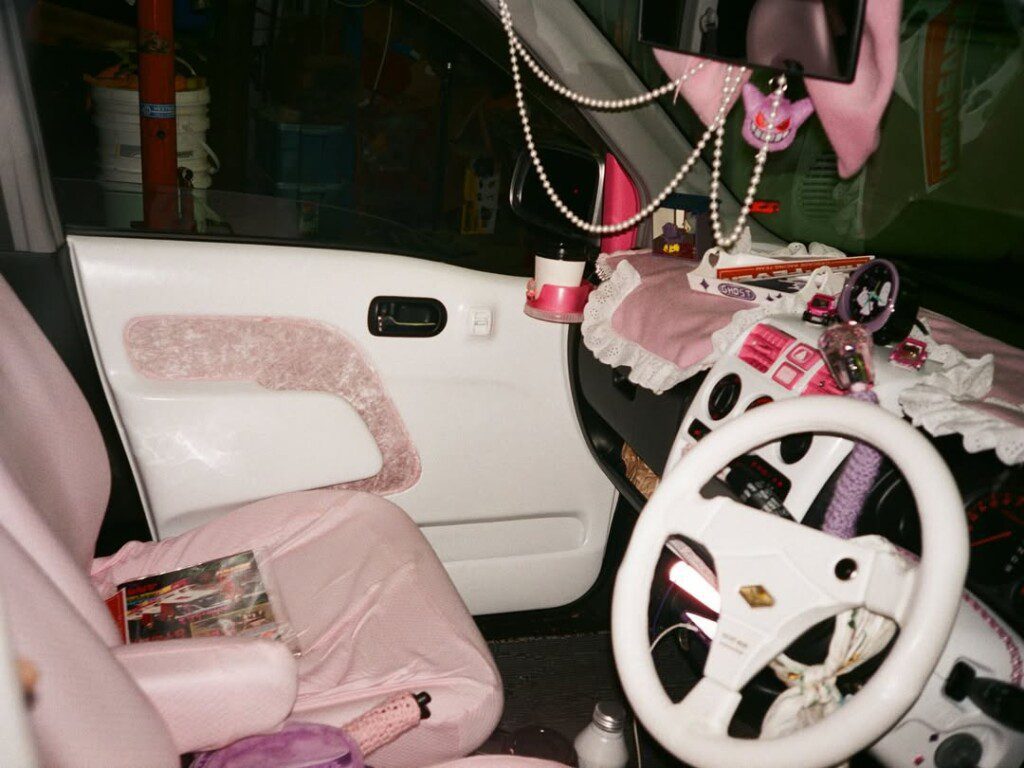Pink-themed car interior with accessories like lace, beads, and mini toys on dashboard and seat.