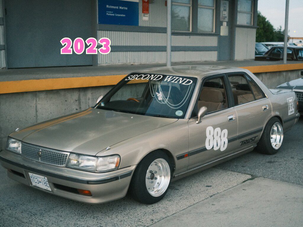 Gold vintage car with Second Wind, number 888, and 2023 text at Richmond Marina parking lot.