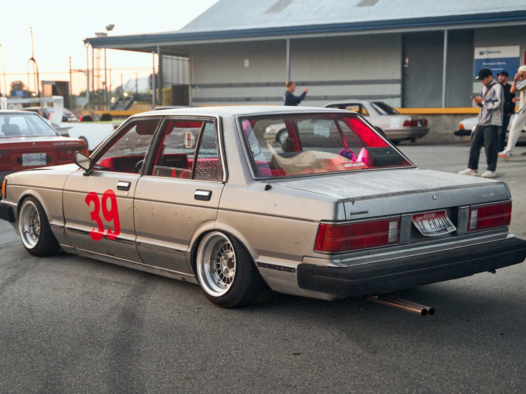 Vintage car with number 39, sporting a lowered stance, parked in an urban setting during a motorsport event.