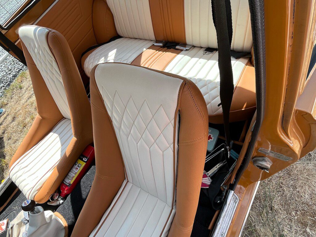 Vintage car interior with tan and white seat upholstery, showcasing a retro design.