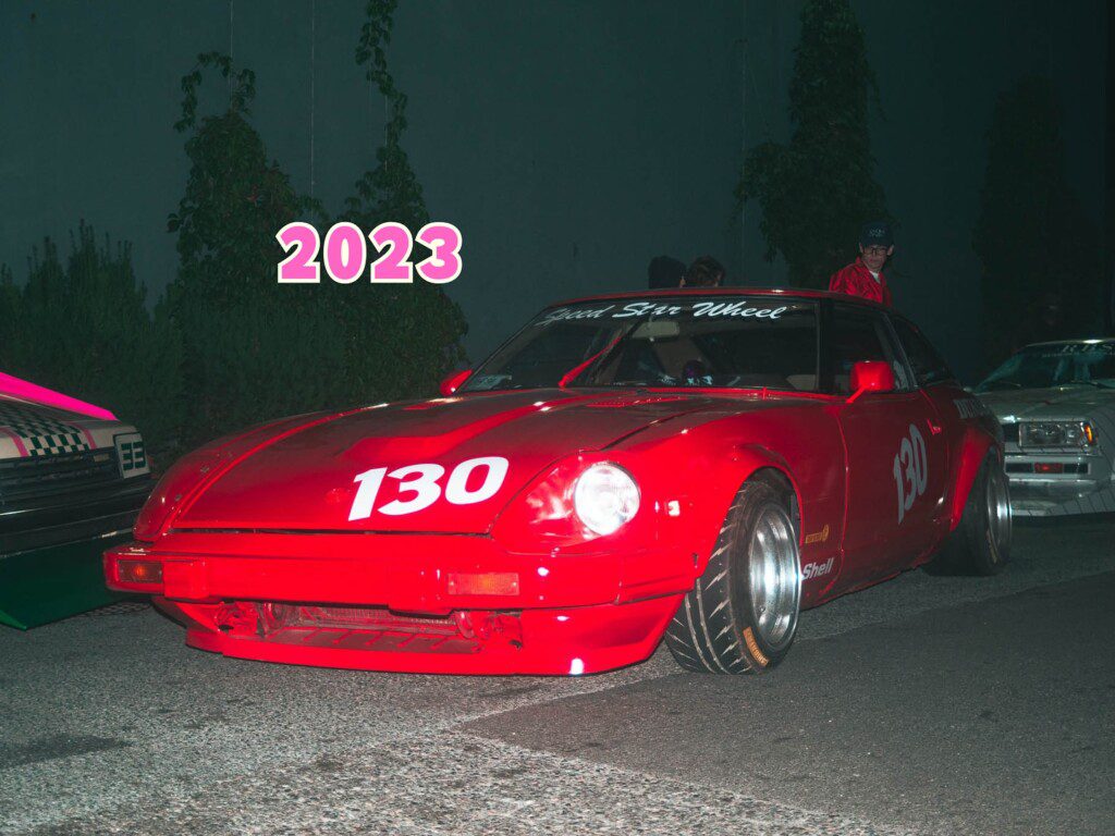 Red sports car with number 130 at night event, 2023. Vibrant and stylish. Perfect for car enthusiasts.