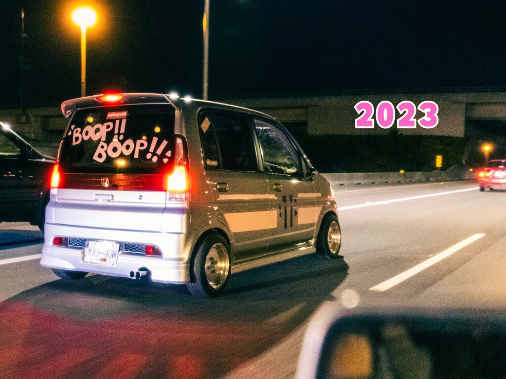 Modified car with Boop!! Boop!! decal driving on highway at night, 2023 text overlay.