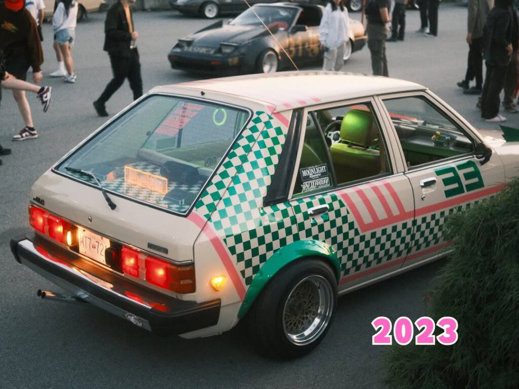 Colorful retro car with checkerboard pattern at a car meet, 2023.