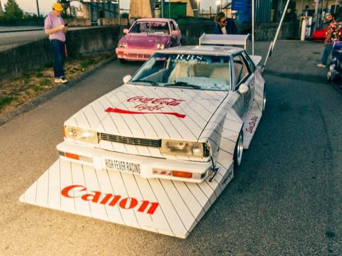 Retro custom car with Coca-Cola and Canon branding on a racetrack.
