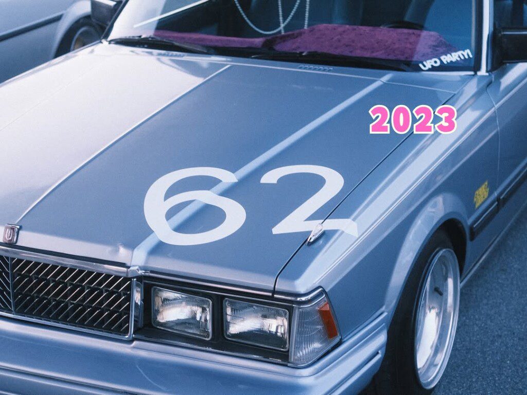 Vintage gray car with number 62 on hood, 2023 in pink. Classic retro style vehicle with highlighted details.