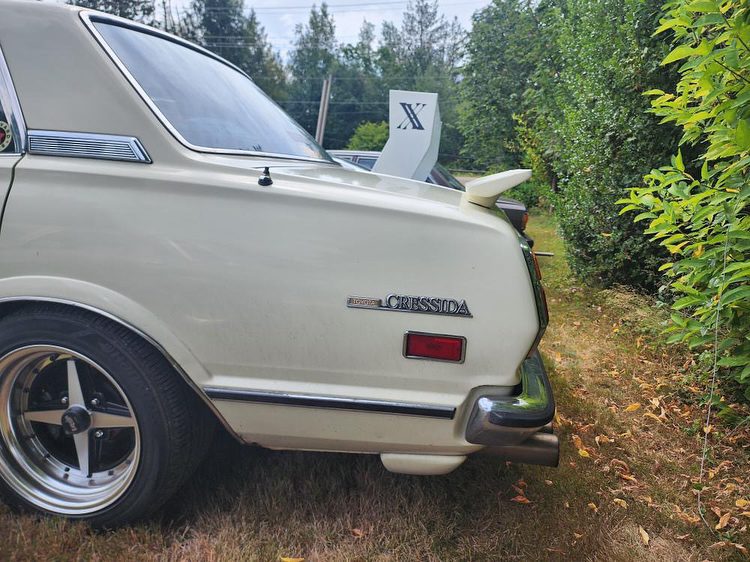 Vintage Toyota Cressida parked, showcasing classic rear design and chrome accents, surrounded by greenery.