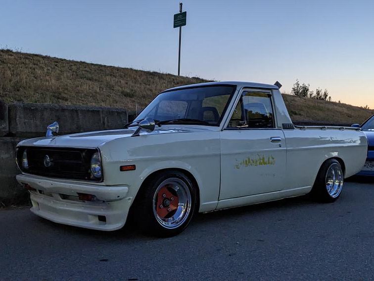 Vintage white pickup truck parked on roadside at dusk, showcasing custom rims and classic design.