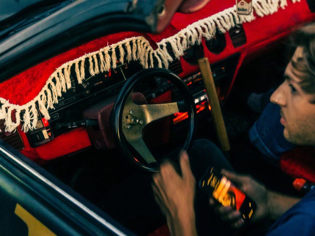 Vintage car interior with decorative dashboard and person holding a smartphone.