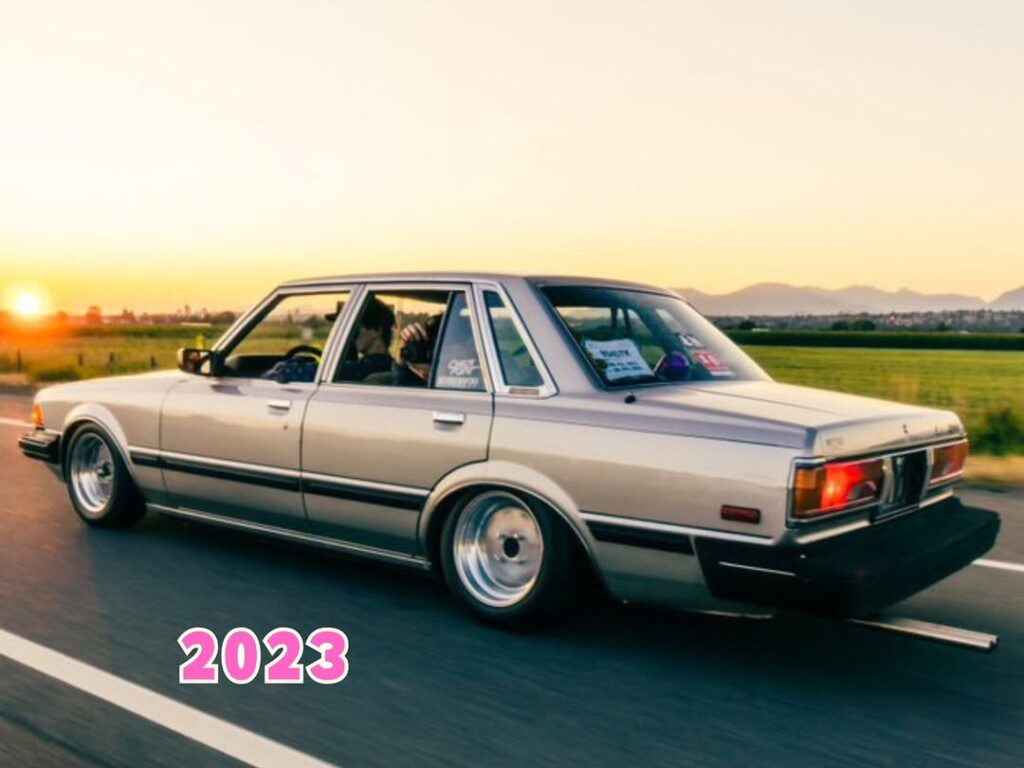 Classic car cruising at sunset with scenic view and '2023' text overlay, emphasizing modern appreciation for vintage autos.