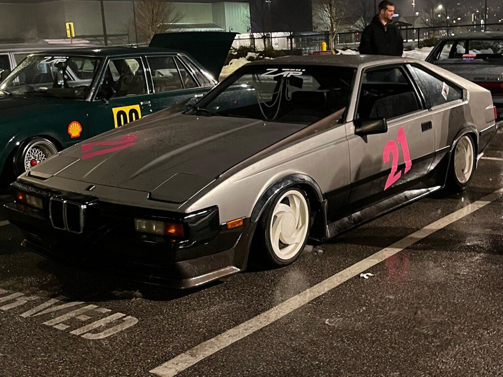 Classic sports car with number 21 parked at night, showcasing sleek design and retro flair.