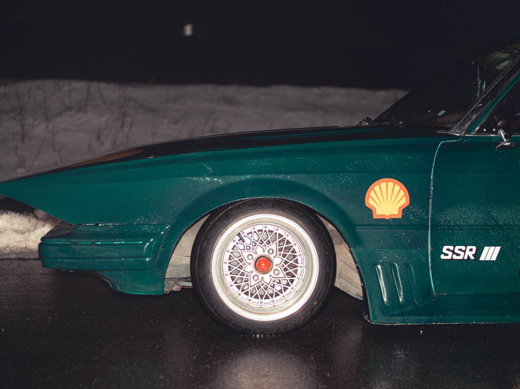 Close-up of vintage green car with Shell and SSR branding, featuring intricate alloy wheel design.