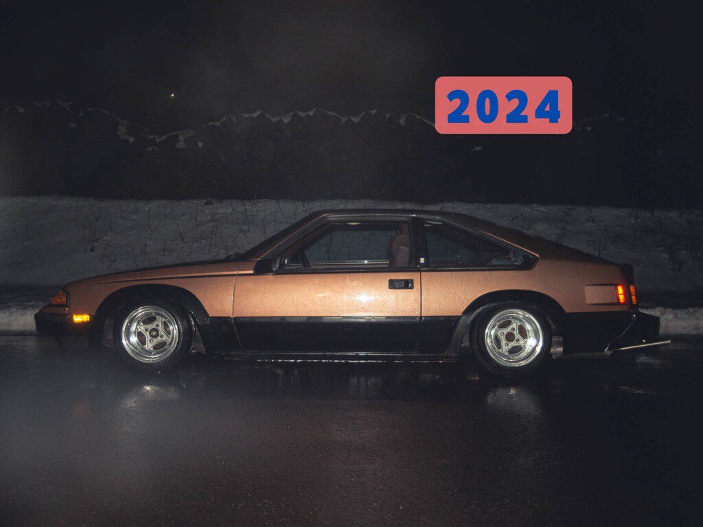 Vintage car in nighttime setting with 2024 text; sleek design with reflective detailing.