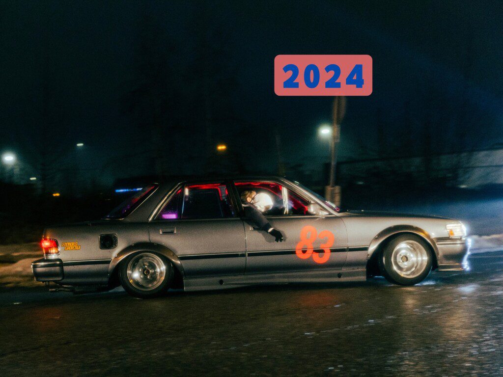Racing car with number 83 drives at night, showcasing 2024 in bold above, highlighting speed and future events.