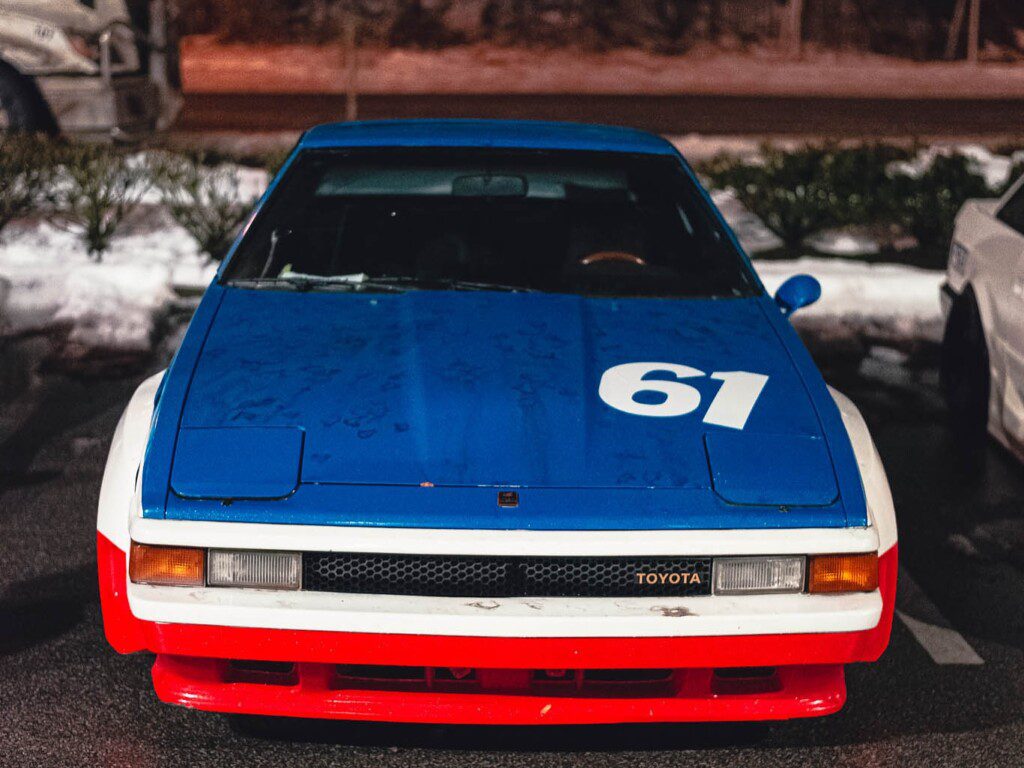 Vintage blue Toyota race car with number 61 parked at night.