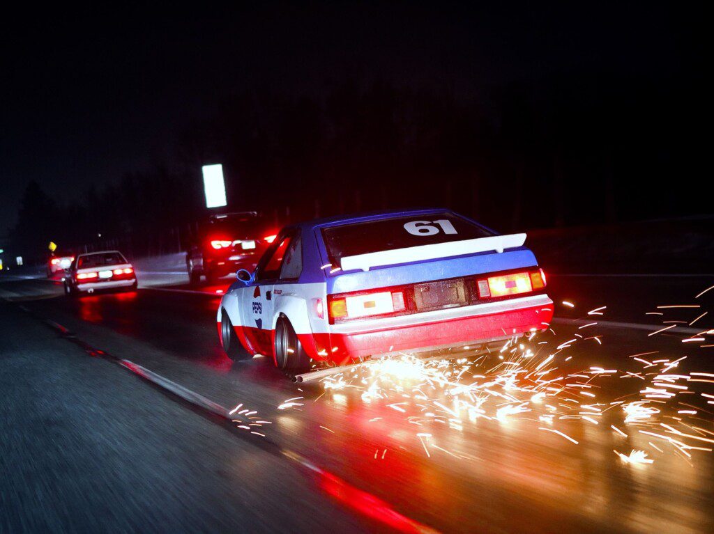 Racing car driving at night with sparks flying, creating a dynamic and thrilling motorsport scene.