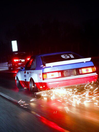 Racing car driving at night with sparks flying, creating a dynamic and thrilling motorsport scene.