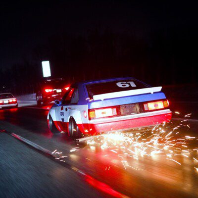 Racing car driving at night with sparks flying, creating a dynamic and thrilling motorsport scene.