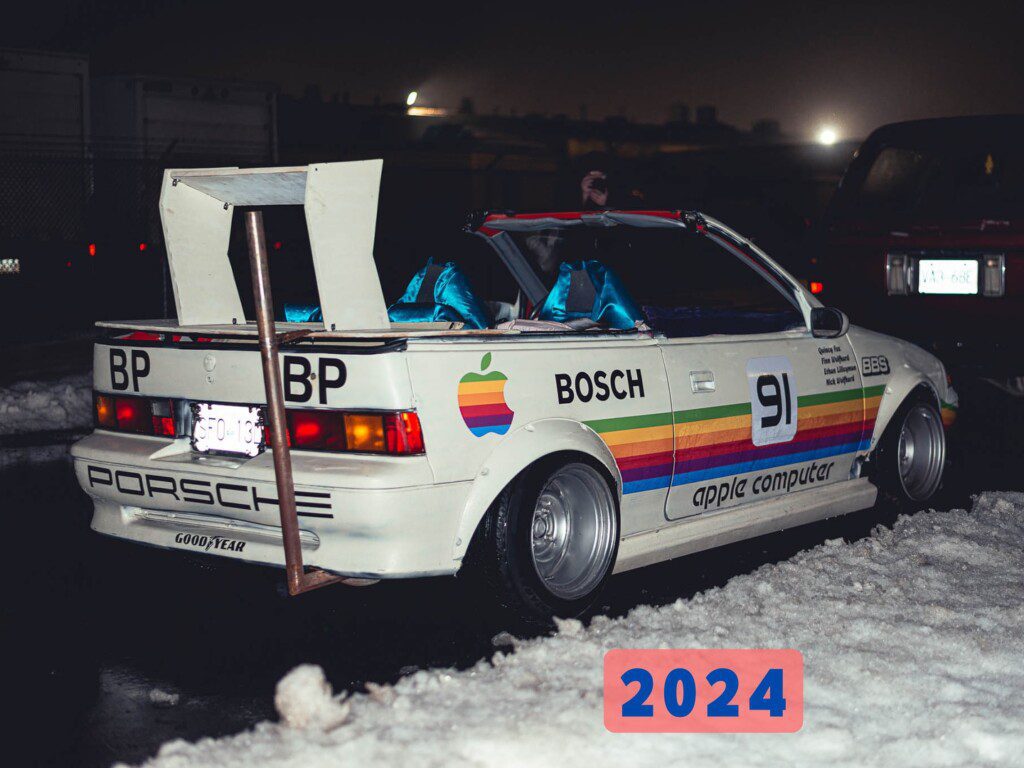 Retro-themed car with Apple and Porsche logos in snowy setting, featuring colorful graphics and a large rear spoiler.