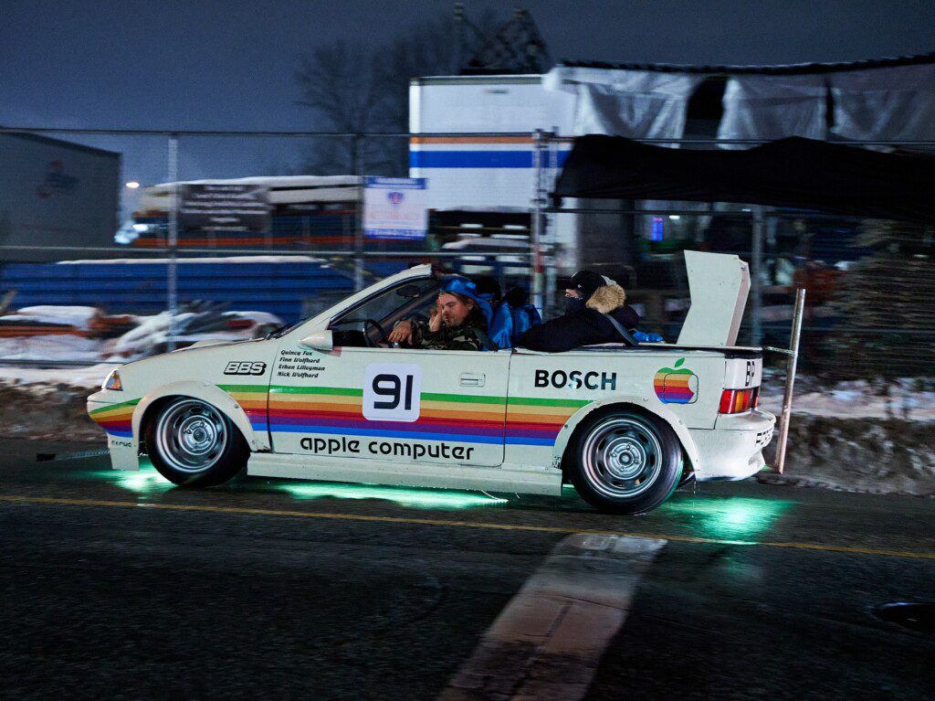 Retro-themed car with Apple logo and neon lights racing at night.