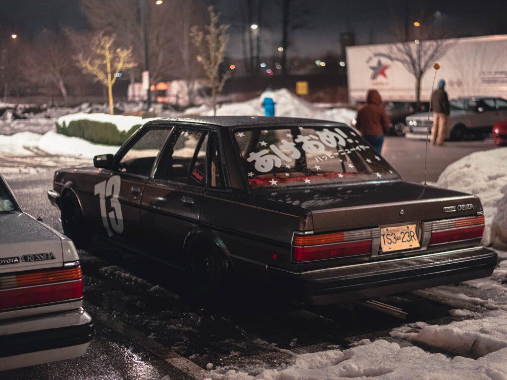 Vintage Toyota Cressida with decals parked at night in a snowy lot.