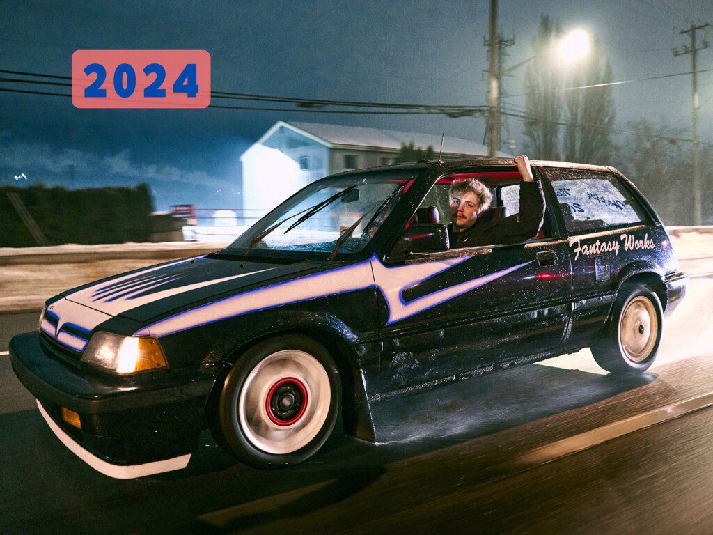 Sporty car with custom design driving at night, marked Fantasy Works and 2024 in sky-blue letters on a pink background.