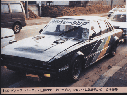 Vintage modified Japanese sedan with colorful decals and a long nose, parked on a street.