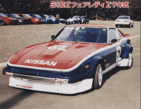 Vintage Nissan S130Z race car with red and blue livery parked on a track, showcasing its classic design and branding.