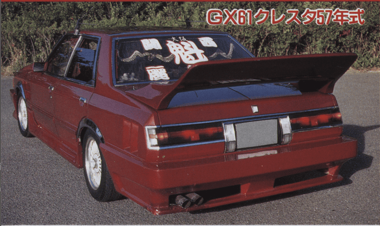 Red GX61 Cresta car with custom rear wing and decals, parked on a road, showcasing its modified aesthetic.