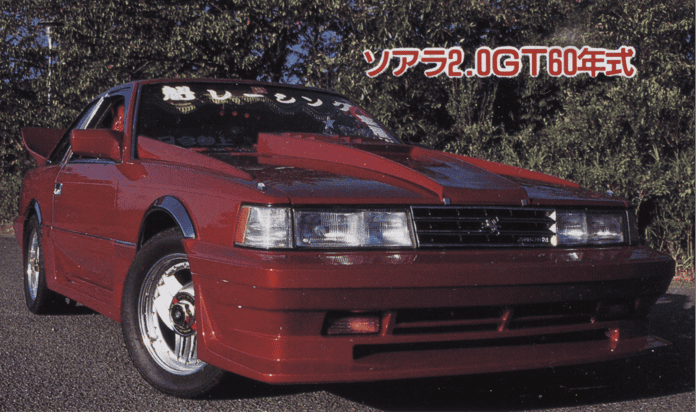 Red vintage sports car with bold design parked outdoors, showcasing front and side details. Japan text overlay above.