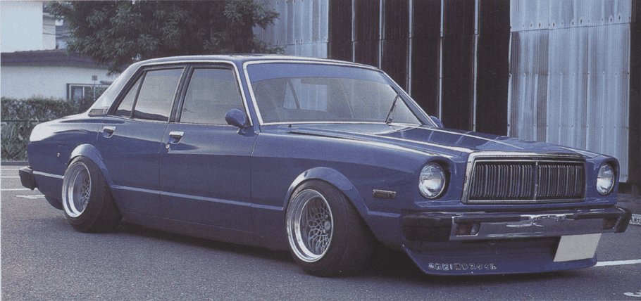 Vintage blue sedan car with custom modifications, parked outdoors, showcasing low stance and classic design.