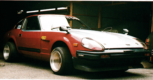 Vintage red sports car with wide rear wheels, parked in a garage, showcasing retro automotive design and style.