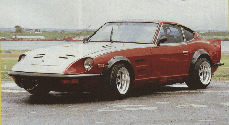 Classic red sports car with sleek design, parked outdoors on a cloudy day, highlighting vintage automotive elegance.