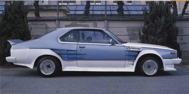 Side view of a custom retro car with sporty body kit, parked on a street with trees in the background.