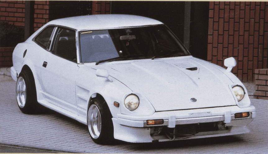 Vintage white sports car parked on a tiled surface, featuring a classic design with aerodynamic body and custom wheels.